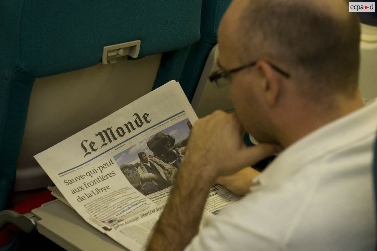 Un ressortissant évacué de Tripoli (Libye) lit un article sur le "Sauve-qui-peut aux frontières libyennes" en une du journal "Le Monde" dans l'avion Airbus A340 de l'escadron de transport 3/60 Esterel.