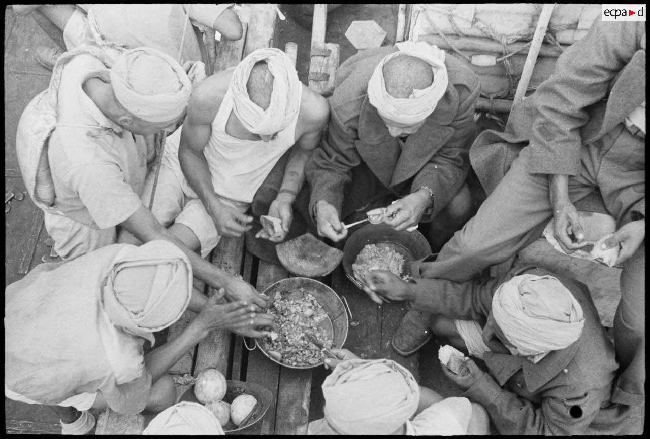 Des tirailleurs du 1er régiment de tirailleurs marocains (RTM) se restaurent sur le pont d'un navire naviguant vers la Corse.
