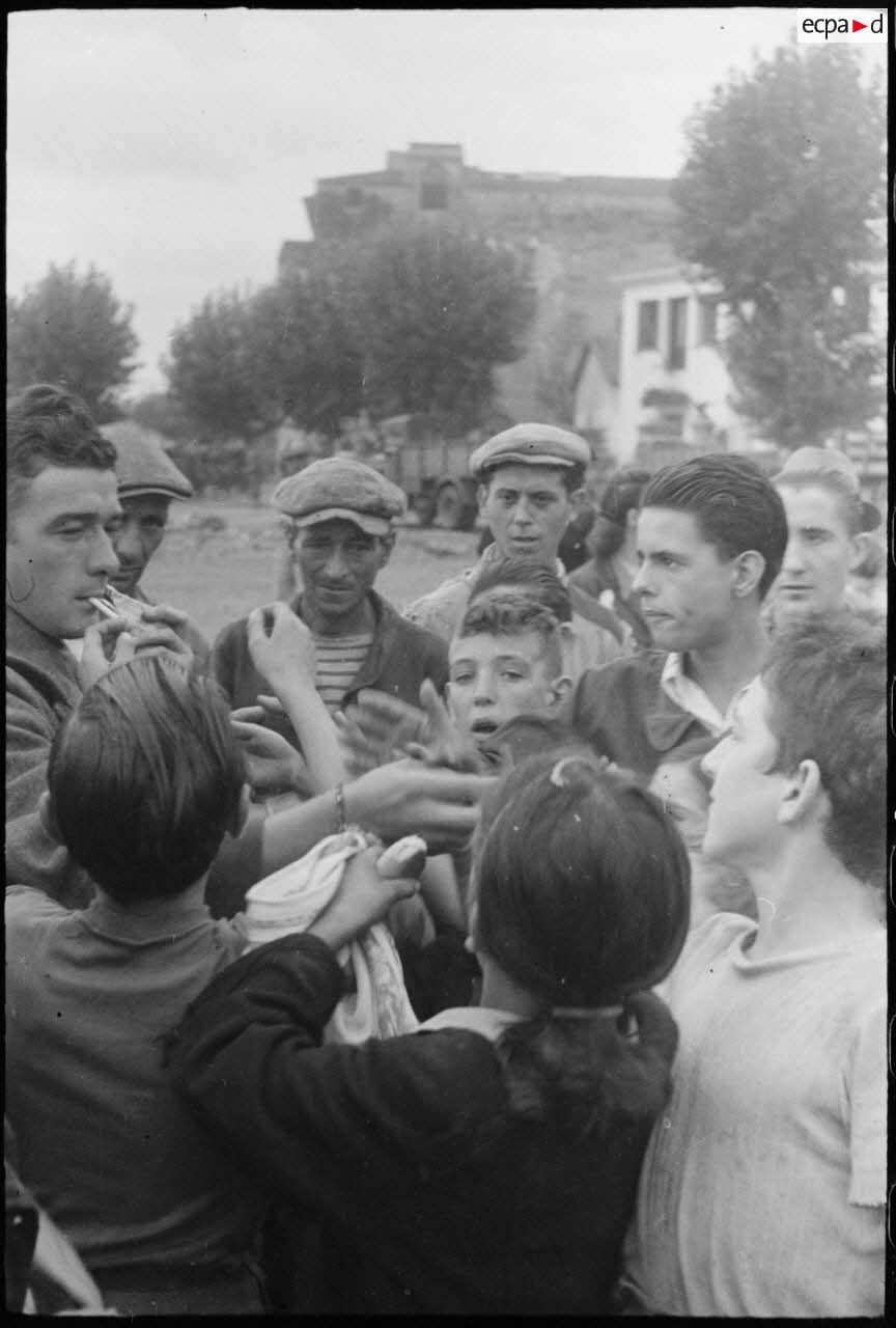Un tirailleur du 1er RTM (régiment de tirailleurs marocains), qui vient de débarquer sur le port avec son unité, distribue des friandises à de jeunes ajacciens qui l'entourent.