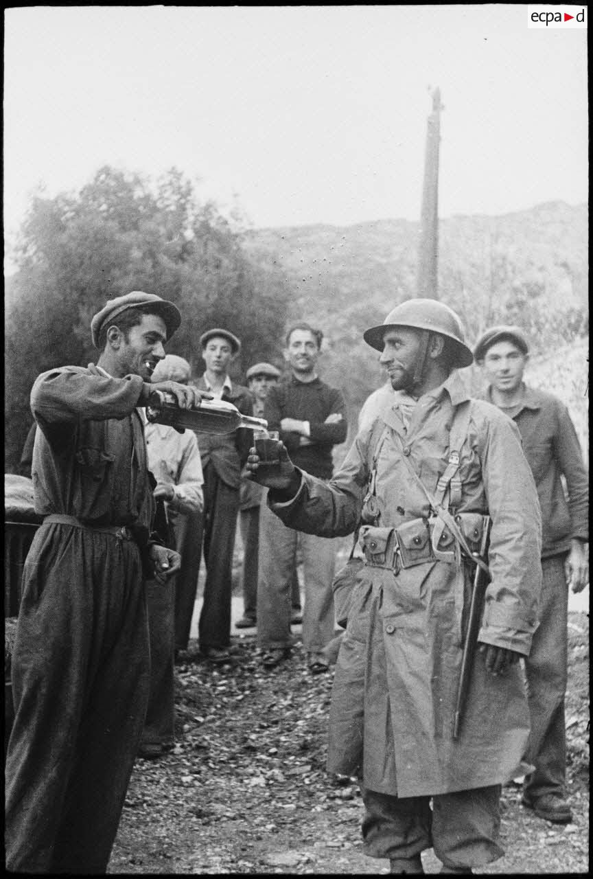 Un habitant du village de Patrimonio libéré offre à boire à un goumier du 2e GTM (groupe de tabors marocains).