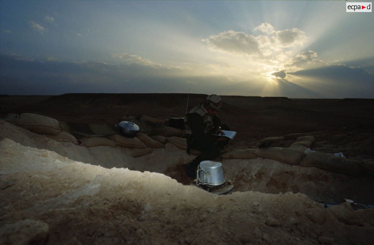 En ZDO (zone de déploiement opérationnel) Olive, trou de combat d'un soldat du 1er RS (régiment de spahis) au repos à l'aube, qui lit ou écoute la radio.