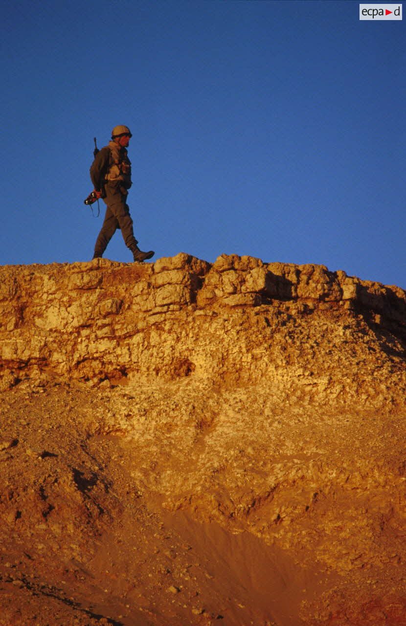 En ZDO (zone de déploiement opérationnel) Olive, un soldat équipé de jumelles est posté en observation au sommet d'une butte.