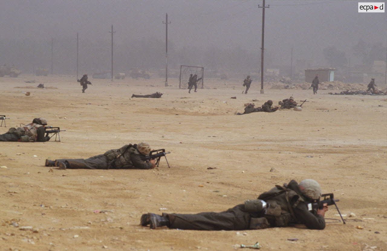 Les marsouins du 3e RIMa (r&eacute;giment d'infanterie de marine) investissent la ville d'Al Salman, certains sont en position de tireur couch&eacute;, arm&eacute;s de fusils d'assaut FAMAS, et appuient d'autres soldats en progression.