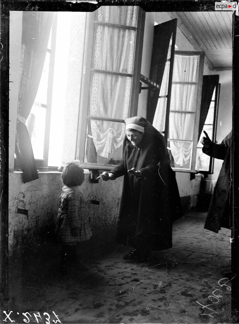 Toul (Meurthe-et-Moselle). Asile de Luxembourg. Croix-Rouge am&eacute;ricaine. Infirmi&egrave;re offrant une pomme &agrave; un b&eacute;b&eacute;. [l&eacute;gende d'origine]