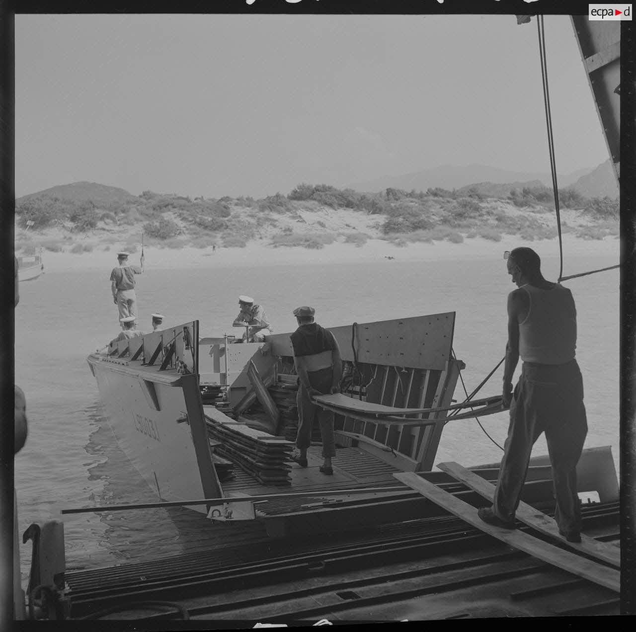 Sur le tournage du film Le jour le plus long. Le matériel (décors) est transporté sur la plage par un engin de débarquement (LCVP L9003.1) de l'Argens.