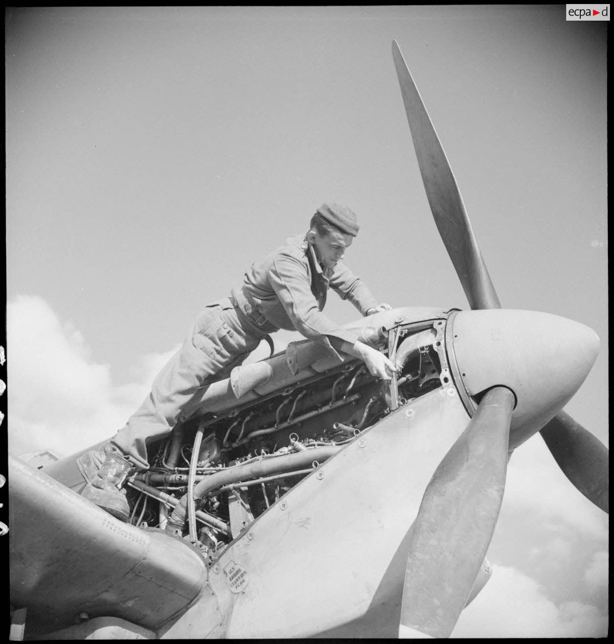 Un mécanicien assure la maintenance du moteur d'un Spitfire Mk V du groupe de chasse (GC) II/7 Nice.