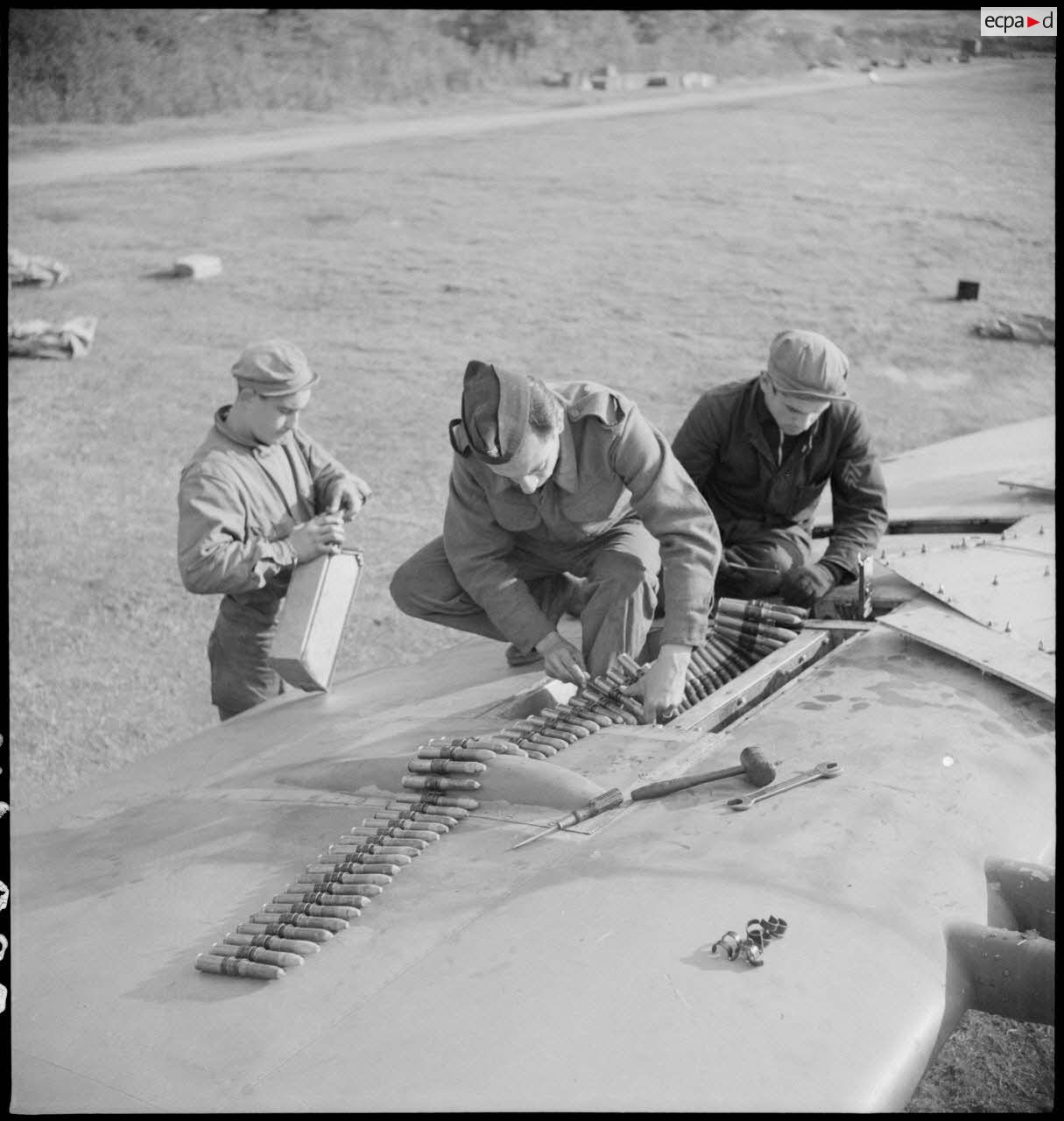 Des mécaniciens du groupe de chasse II/7 Nice approvisionnent en munitions une des mitrailleuses d'aile d'un Spitfire Mk V après un retour de mission.