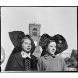 Portrait de jeunes Alsaciennes à l'occasion de Noël dans le village de Masevaux en ruine. A l'arrière plan, le clocher de l'église Saint-Martin.