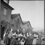 Photographie de groupe de soldats, dont des personnels du SCA (Service cinématographique de l'armée), posant avec de jeunes Alsaciennes à l'occasion de Noël.