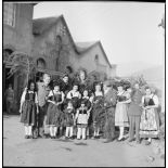 Photographie de groupe de soldats, dont des personnels du SCA (Service cinématographique de l'armée), posant avec de jeunes Alsaciennes à l'occasion de Noël.