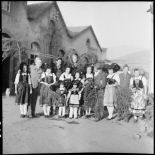 Photographie de groupe de soldats, dont des personnels du SCA (Service cinématographique de l'armée), posant avec de jeunes Alsaciennes à l'occasion de Noël.
