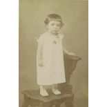 [Portrait d'un enfant en robe blanche debout sur une chaise].