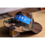Bandeau portant le logo et le slogan de la Radio Azur FM, la radio sans nuages, sur un chapeau.