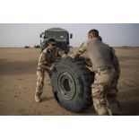 Des mécaniciens acheminent la roue crevée d'un VAB vers un camion GBC-180 lors d'une intervention technique dans le désert.