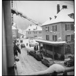 Vue en plongée d'une rue enneigée de Maîche avec les voitures des autorités civiles et militaires venues rendre visite à la 1re Armée au PC de la 9e DIC (division d'infanterie coloniale) installé au château de Montalembert.