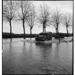 Des half-tracks du 64e RADB traversent une zone inondée aux abords de l'Ill.