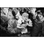 Pierre Bourdan porte une enfant revêtue du costume traditionnel alsacien dans la commune de Erstein (Bas-Rhin) libérée.