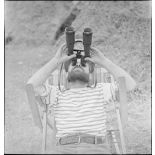 Un marin, appartenant à la 4e batterie de 90 mm contre avions, batterie mobile de défense antiaérienne de la Marine, observe le ciel à l'aide d'une paire de jumelles.