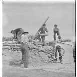 Des marins, appartenant à la 4e batterie mobile de défense antiaérienne de la Marine, effectuent des travaux de terrassement et empilent des sacs de sable afin de consolider la protection autour d'un canon antiaérien de 90 mm.