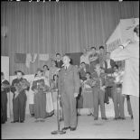 Un militaire parle au micro sur la scène du théâtre.