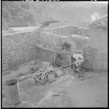 Centre de regroupement de Boudjebâa. Un habitant travaillant dans sa cour.