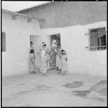 Centre de regroupement de M'Cid. Cour intérieure et entrée d'un logement. Sur le pas de la porte des fillettes et leur mère.