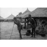 République centrafricaine, Domété à 60 km de Bangui, 1942. Féticheur aspergeant une malade avec une macération de plantes dans de l'eau chaude.