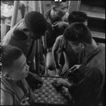 Des prisonniers libérés par le Vietminh jouant aux dames à bord d'un chaland de débarquement les rapatriant vers Haïphong.