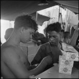 Des prisonniers libérés par le Vietminh perçoivent des paquets de cigarettes à bord d'un chaland de débarquement les rapatriant vers Haïphong.