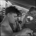 Des prisonniers libérés par le Vietminh perçoivent des paquets de cigarettes à bord d'un chaland de débarquement les rapatriant vers Haïphong.