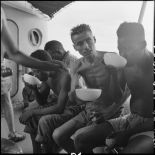 Des prisonniers libérés par le Vietminh en train de boire dans un bol sur un chaland de débarquement les rapatriant vers Haïphong.