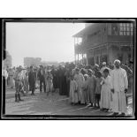 Port-Saïd, 7 h 20. La foule près d'un trou de bombe. A droite, le café près duquel la bombe est tombée (6 morts). [légende d'origine]