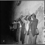 Les parachutistes du 3e régiment de parachutistes coloniaux (3e RPC) opèrent un bouclage et un contrôle d'identité surprise de nuit, à l'angle de la rue de la Bombe et de la rue Mannol. Les suspects sont placés dos au mur, mains sur la tête.