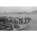 Des soldats et des chevaux traversent le cours d’eau à bord d’une barge.