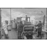 Des marins manoeuvrent un grenadeur de sillage - à chaînes à maillons avec engrenage Galle - de grenades sous-marines, à bord d'un chasseur de mines ou de sous-marins de la Marine nationale.