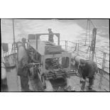 Des marins manoeuvrent un grenadeur de sillage - à chaînes à maillons avec engrenage Galle - de grenades sous-marines à bord d'un un chasseur de mines ou de sous-marins de la Marine nationale.