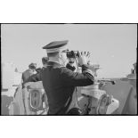Le capitaine de vaisseau Yves Hamon, commandant le croiseur la Marseillaise, observe l'horizon aux jumelles.