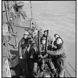 Des canonniers mettent en oeuvre une mitrailleuse double Hotchkiss de 13,2 mm de défense antiaérienne à bord d'un torpilleur léger.
