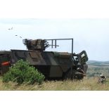 Canon de 20 mm monté sur VAB (véhicule de l'avant blindé) éjectant des douilles avec deux soldats observant l'objectif.