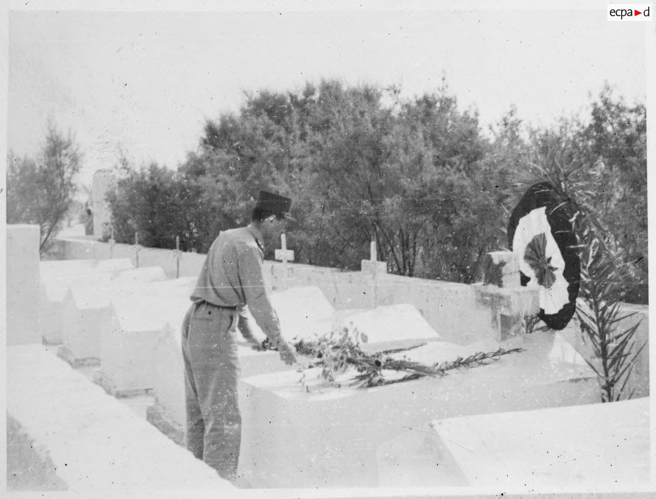 Le général Philippe Leclerc dépose une gerbe sur une tombe, dans un cimetiere du Fezzan.