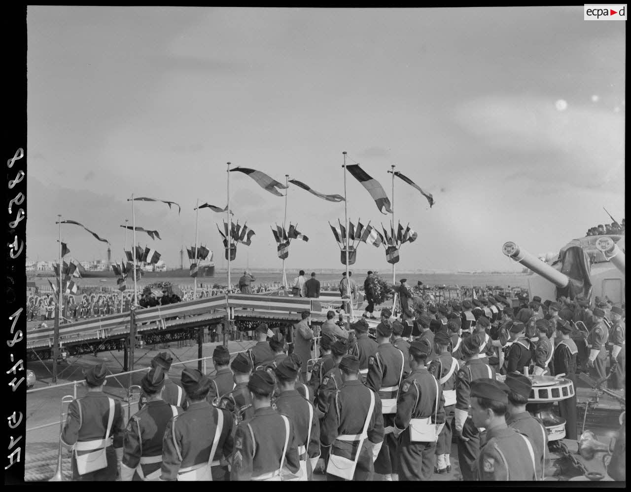 Des soldats transportent les cercueils du général Philippe Leclerc et de ses compagnons, à bord d'un croiseur, à quai, sur le port d'Alger.