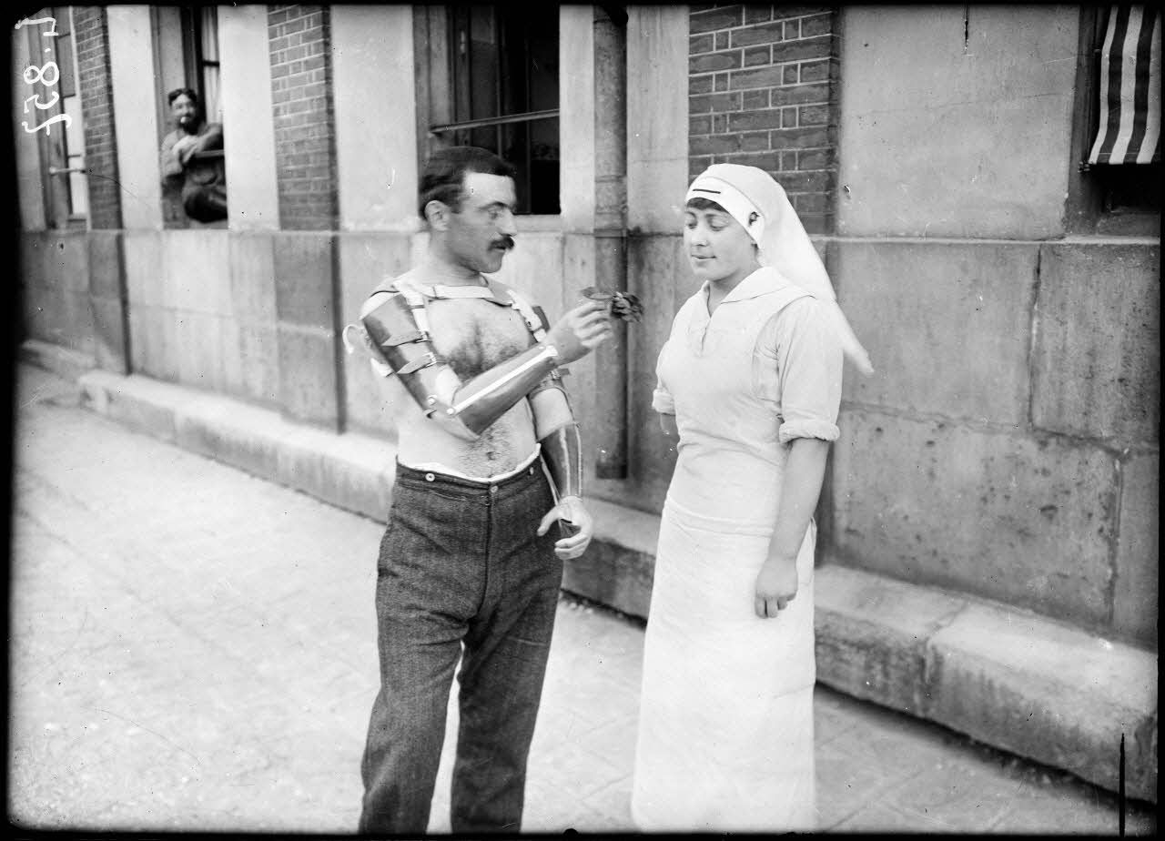 Saint-Maurice. Hôpital militaire 5 bis. Le soldat Bravais représenté déshabillé, offrant avec ses mains artificielles, une fleur à l'infirmière. [légende d'origine]