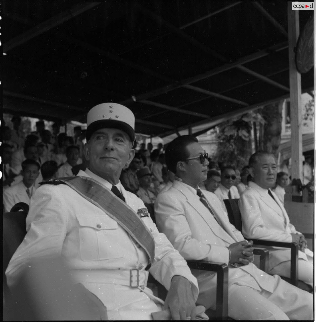 Le général de Lattre de Tassigny, commandant en chef en Indochine,  M. Bao Daï, chef de l'Etat du Vietnam, et M. Tran Van Huu, président du conseil des ministres de l'Etat du Vietnam, dans la  tribune officielle du 14 juillet 1951 à Hanoï.