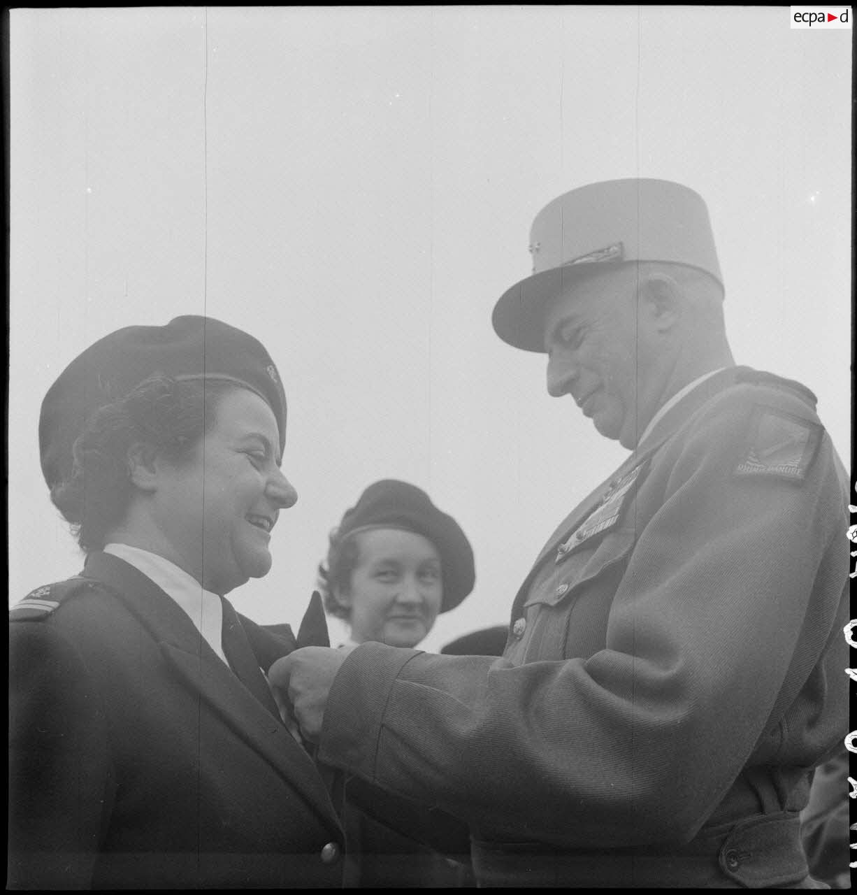 General de Linarès decorates a female soldier, head of the PFAT-Tonkin detachment, during the PFAT (female personnel of the Army) parade at the Mangin stadium.