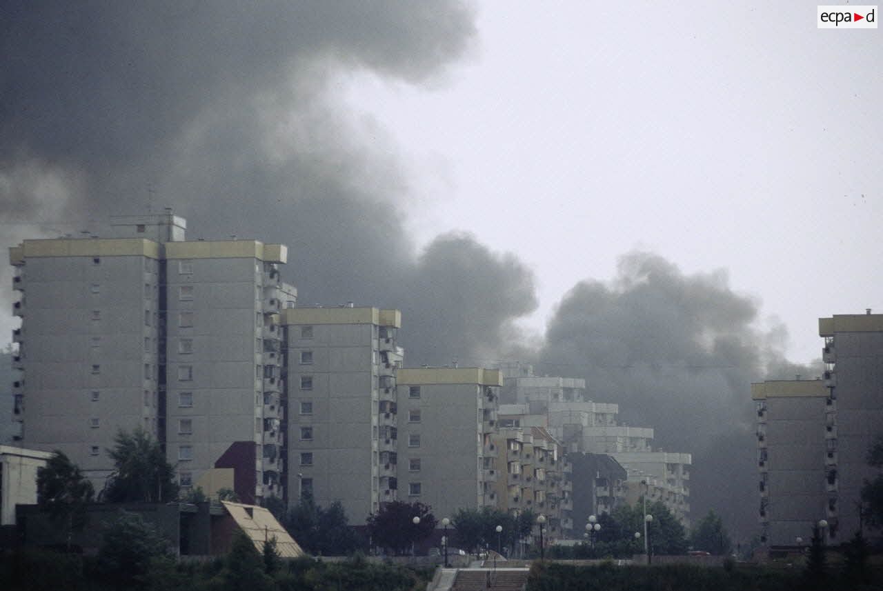 Un nuage de fumée s'élève derrière les immeubles dévastés par les tirs d'artillerie dans Sarajevo.