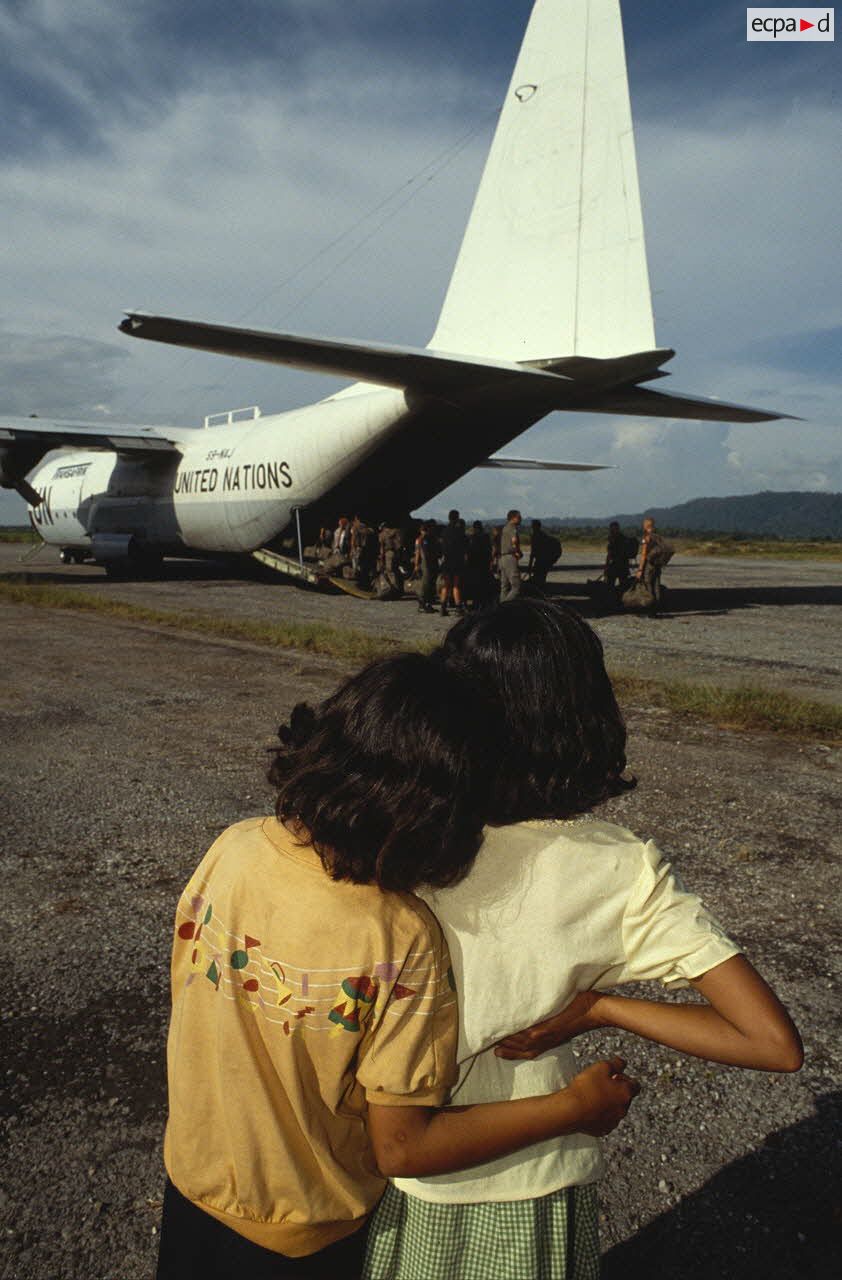 Les enfants cambodgiens saluent les soldats français qui embarquent à bord d'un Hercule C-130.