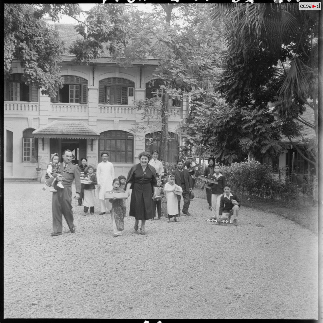 L'épouse du général Cogny (au centre au premier rang), commandant en chef des FTNV (forces terrestres du Nord-Vietnam), devant une bâtisse lors d'une fête de Noël.