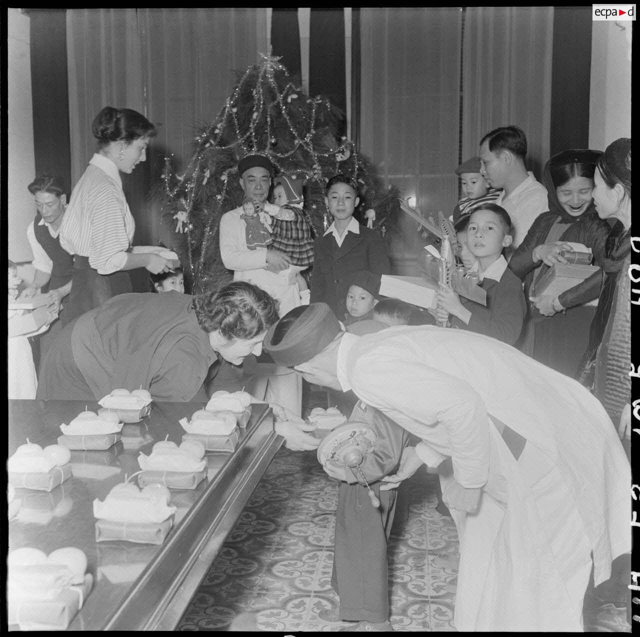 La fille et l'épouse du général Cogny, commandant en chef des FTNV (forces terrestres du Nord-Vietnam), remettent des cadeaux à des enfants vietnamiens lors d'une fête de Noël.