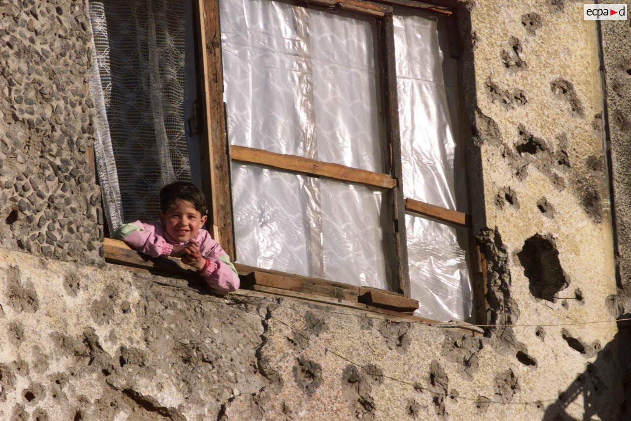 Un enfant afghan à la fenêtre d'un immeuble criblé de balles.