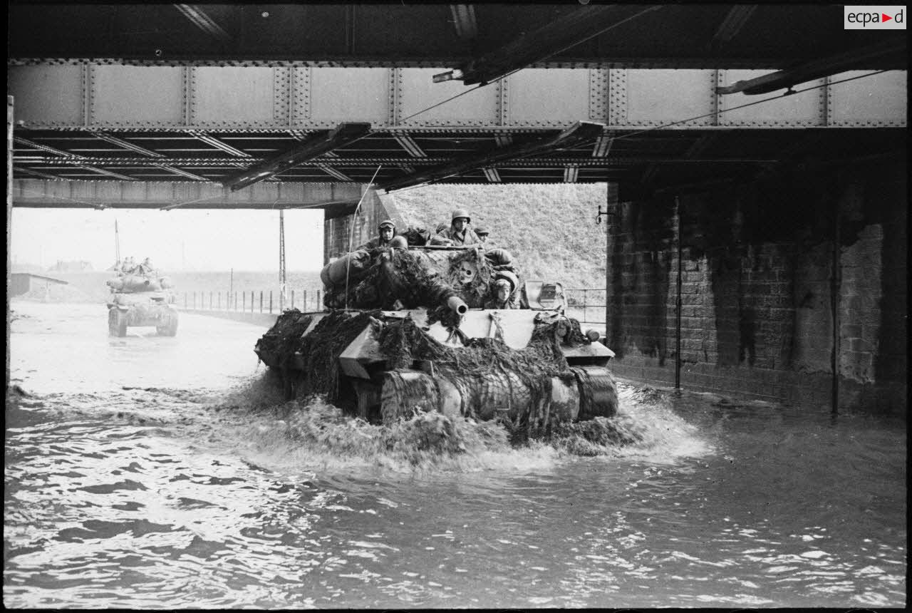 Eléments du GTV, le groupement tactique du colonel de Guillebon, abordant Strasbourg par le faubourg de Cronenbourg envahi par les eaux de l'Ill en crue et passant sous un pont ferroviaire.